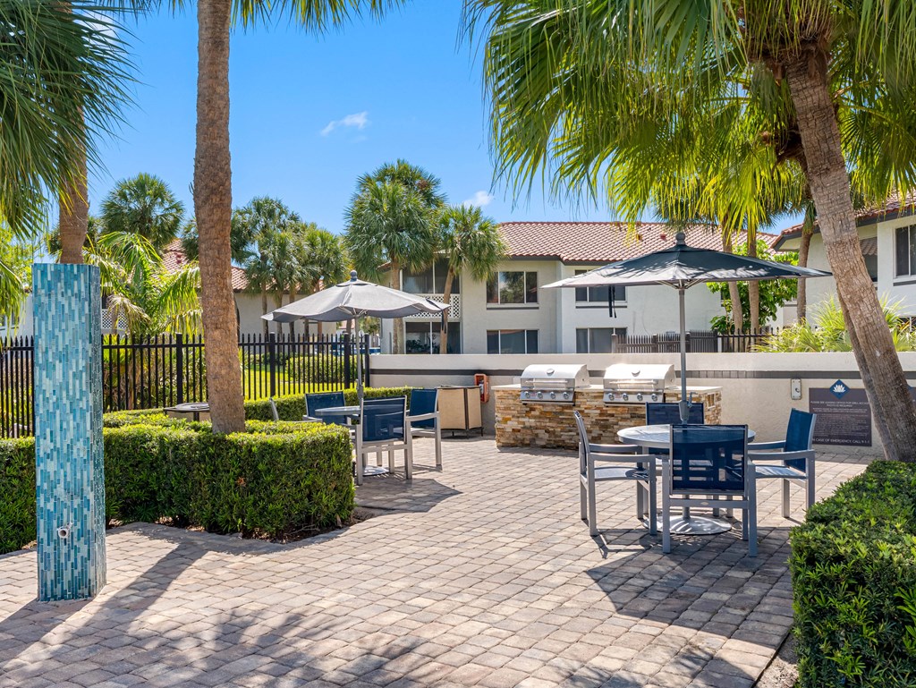 A patio with a table and chairs surrounded by palm trees.
